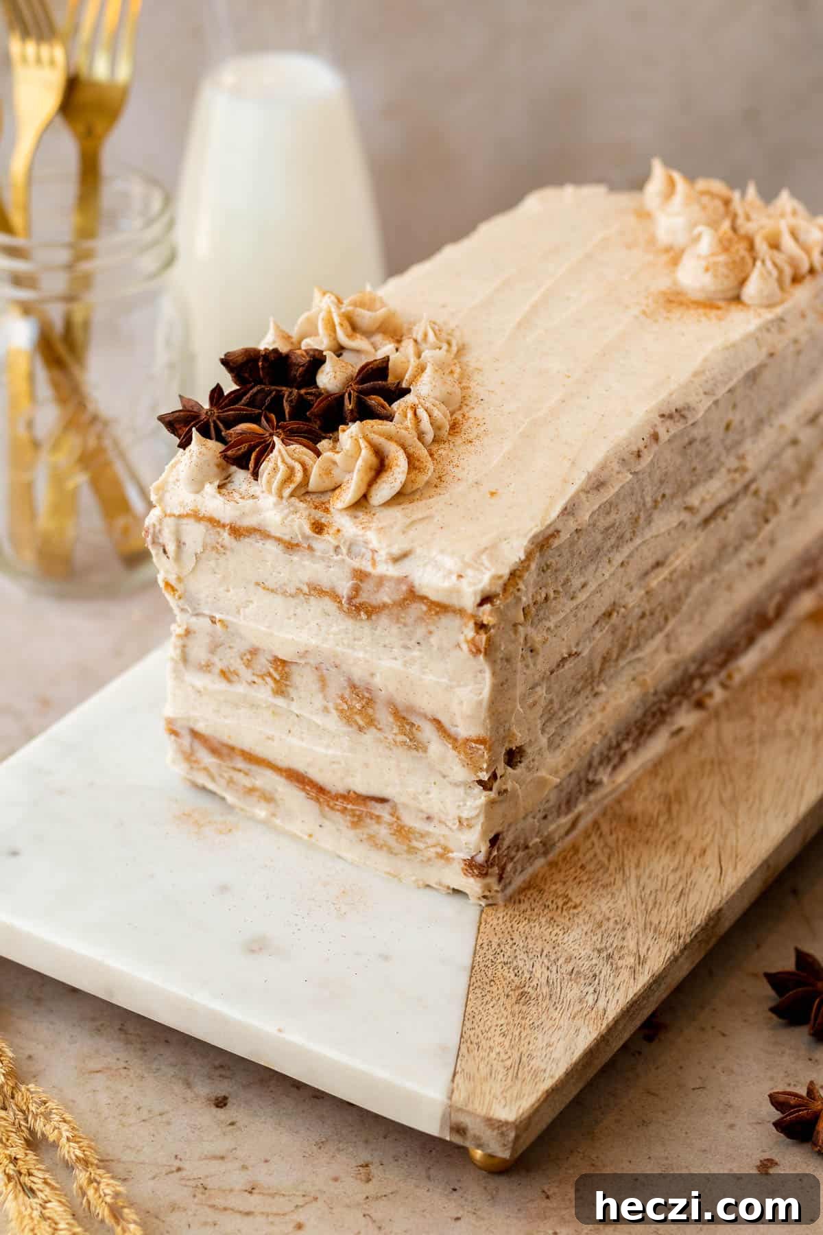 rectangle chai layer cake on wood and marble cutting board with glass of milk and glass of forks in background