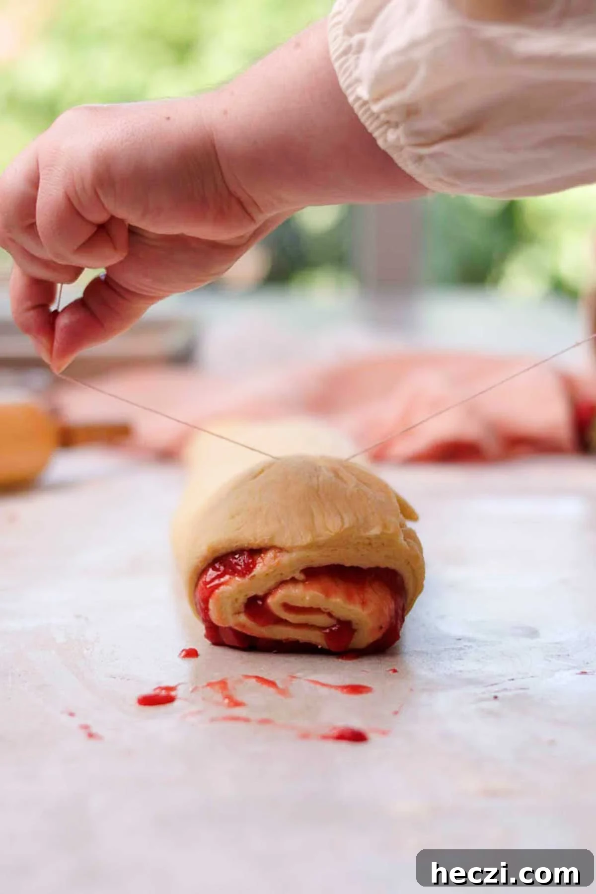 Strawberry Cinnamon Rolls with Cream Cheese Glaze 15 cutting strawberry cinnamon rolls with a string