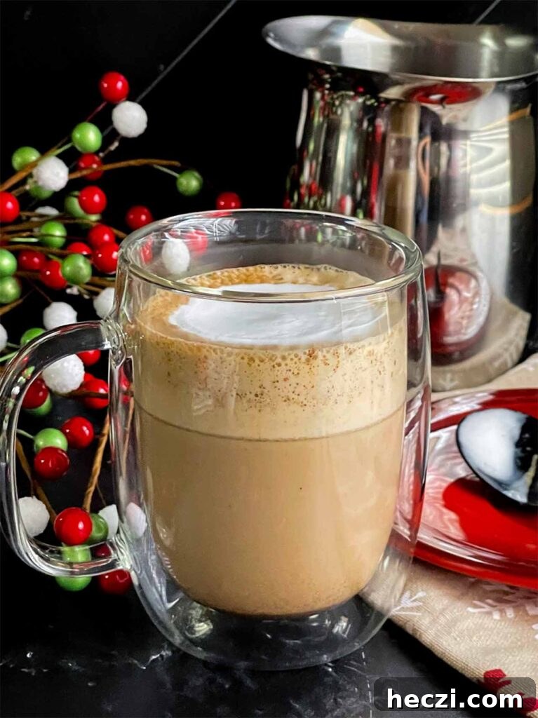 Homemade Holiday Spice Flat White Recipe 11 Holiday spice flat white in a glass mug. A spoon resting in a small red plate to the side.