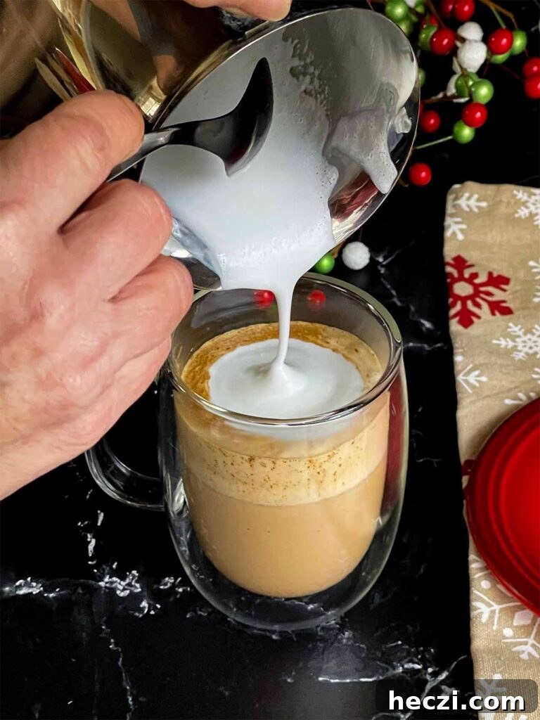 Homemade Holiday Spice Flat White Recipe 9 Steamed milk and foam being poured into the glass mug.