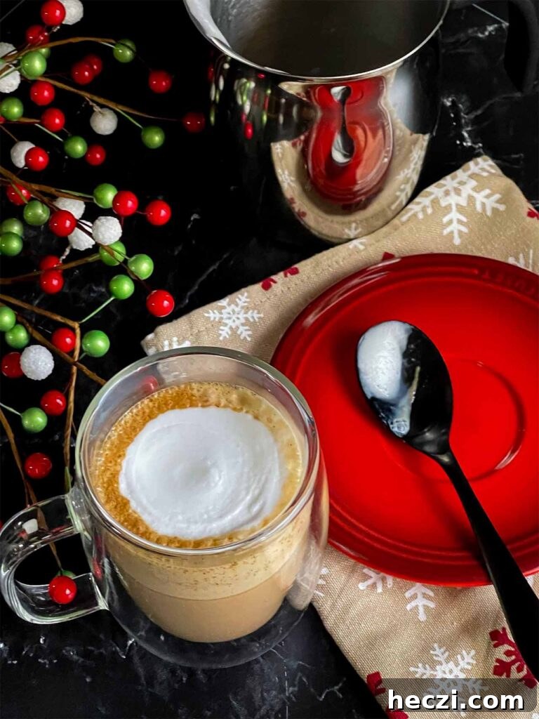 Homemade Holiday Spice Flat White Recipe 10 Holiday spice flat white in a glass mug. A spoon resting in a small red plate to the side.