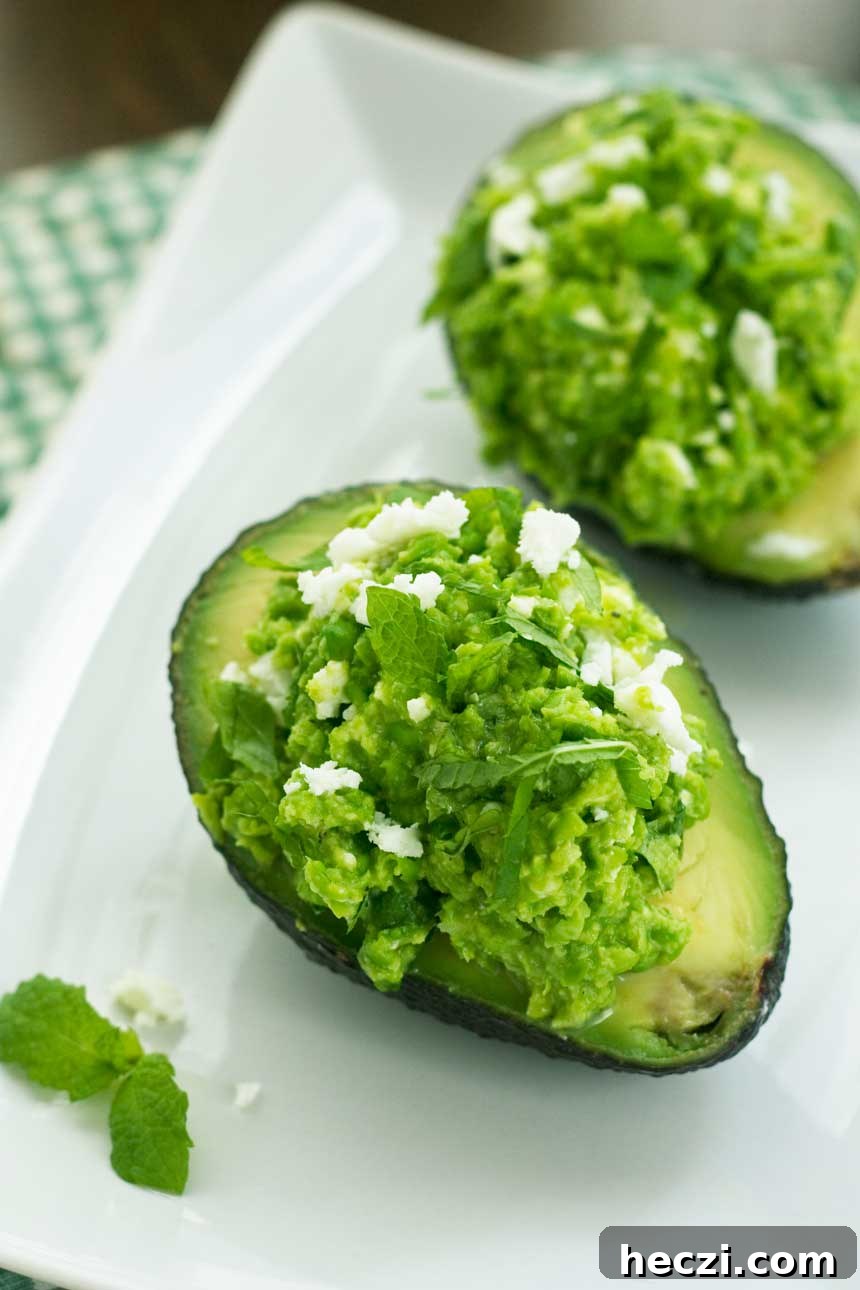 Pea, Mint & Feta Avocado Boats: Fresh Stuffed Avocado Recipe 3 Overhead view of Pea, mint and feta avocado boats on a white plate.