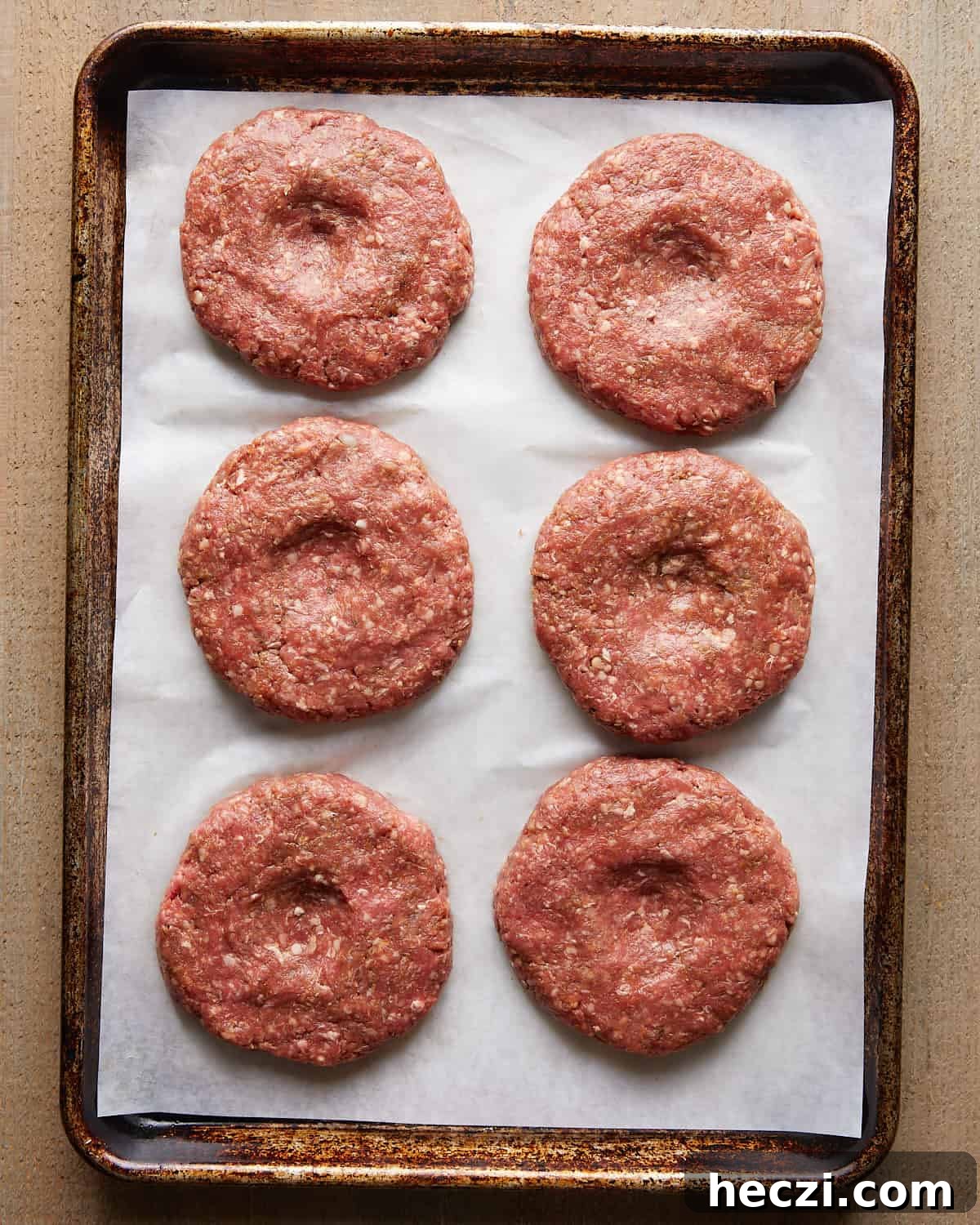 Juicy Grilled Hamburger Recipe for Perfect Summer BBQ 5 Raw burger patties shaped and arranged on parchment paper.