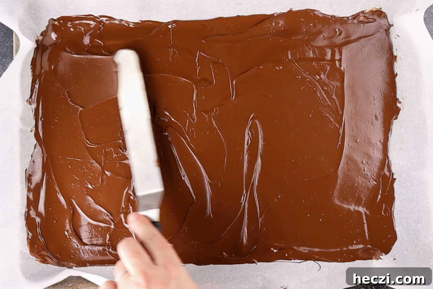 Homemade Peppermint Bark Recipe: Quick Holiday Chocolate Candy 6 spreading melted chocolate onto a baking sheet.