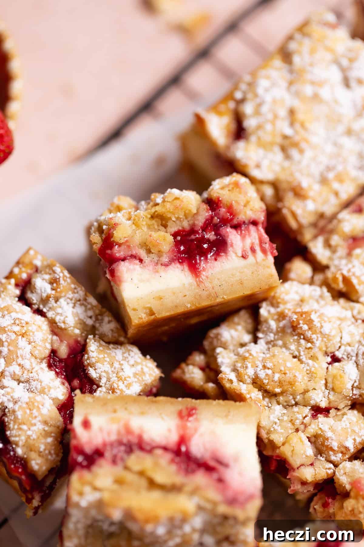 Strawberry cheesecake bar with powdered sugar on a cooling rack.