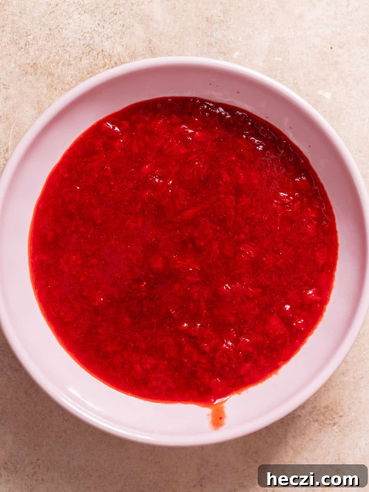 Homemade strawberry jam filling in a bowl for strawberry cheesecake bars.