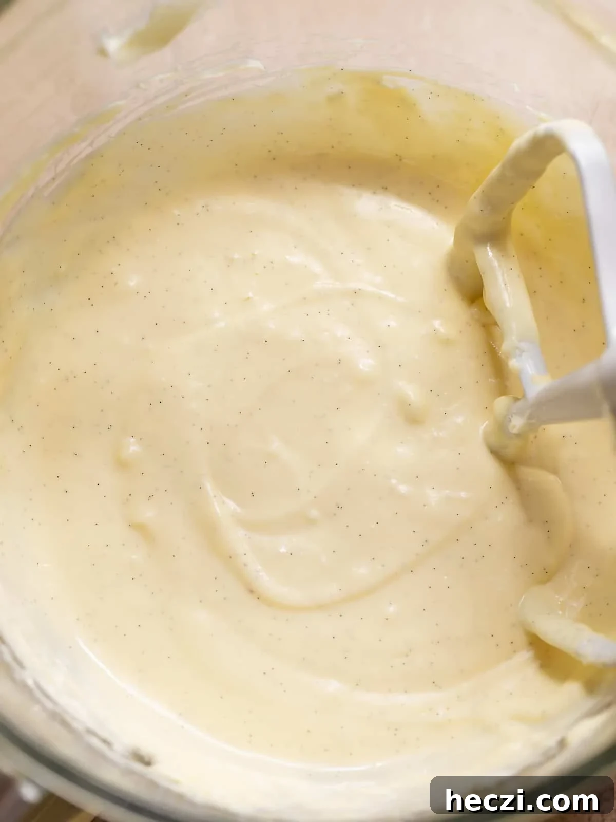 Creamy vanilla bean cheesecake filling mixed in a glass bowl.