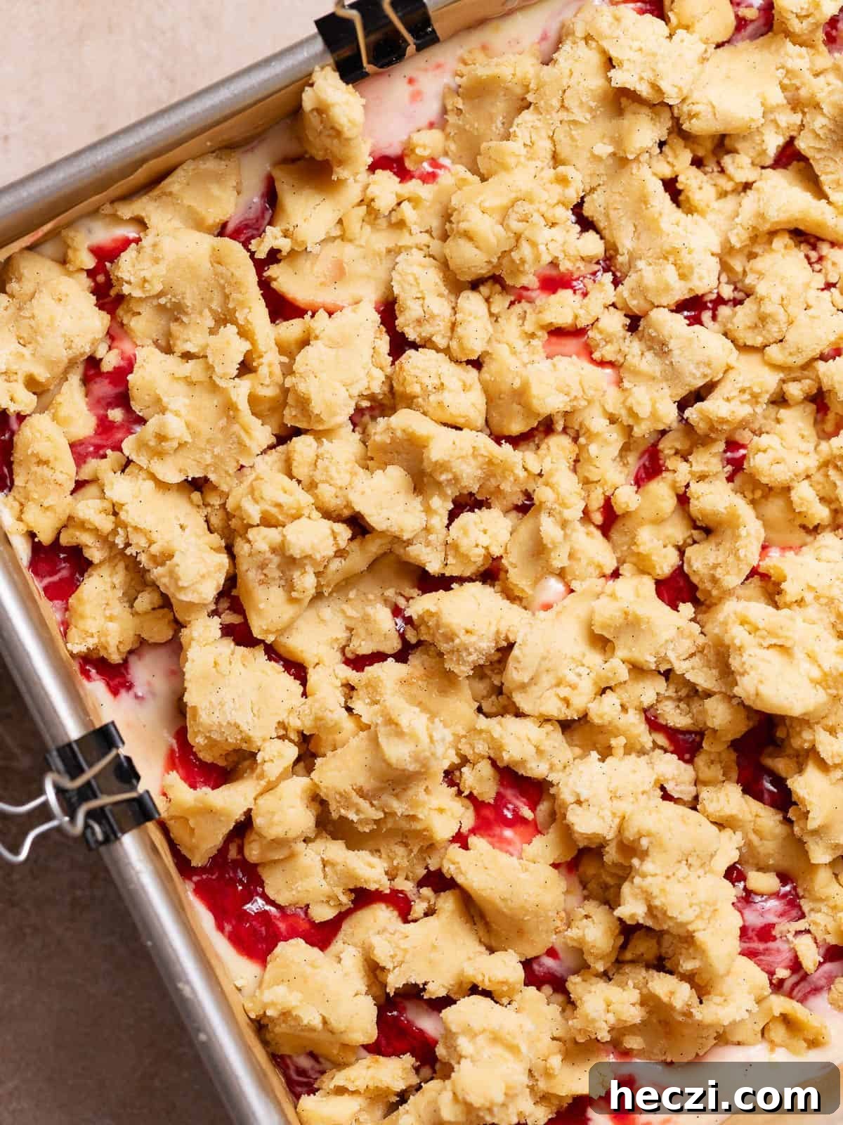 Strawberry cheesecake bars topped with crumble before baking.