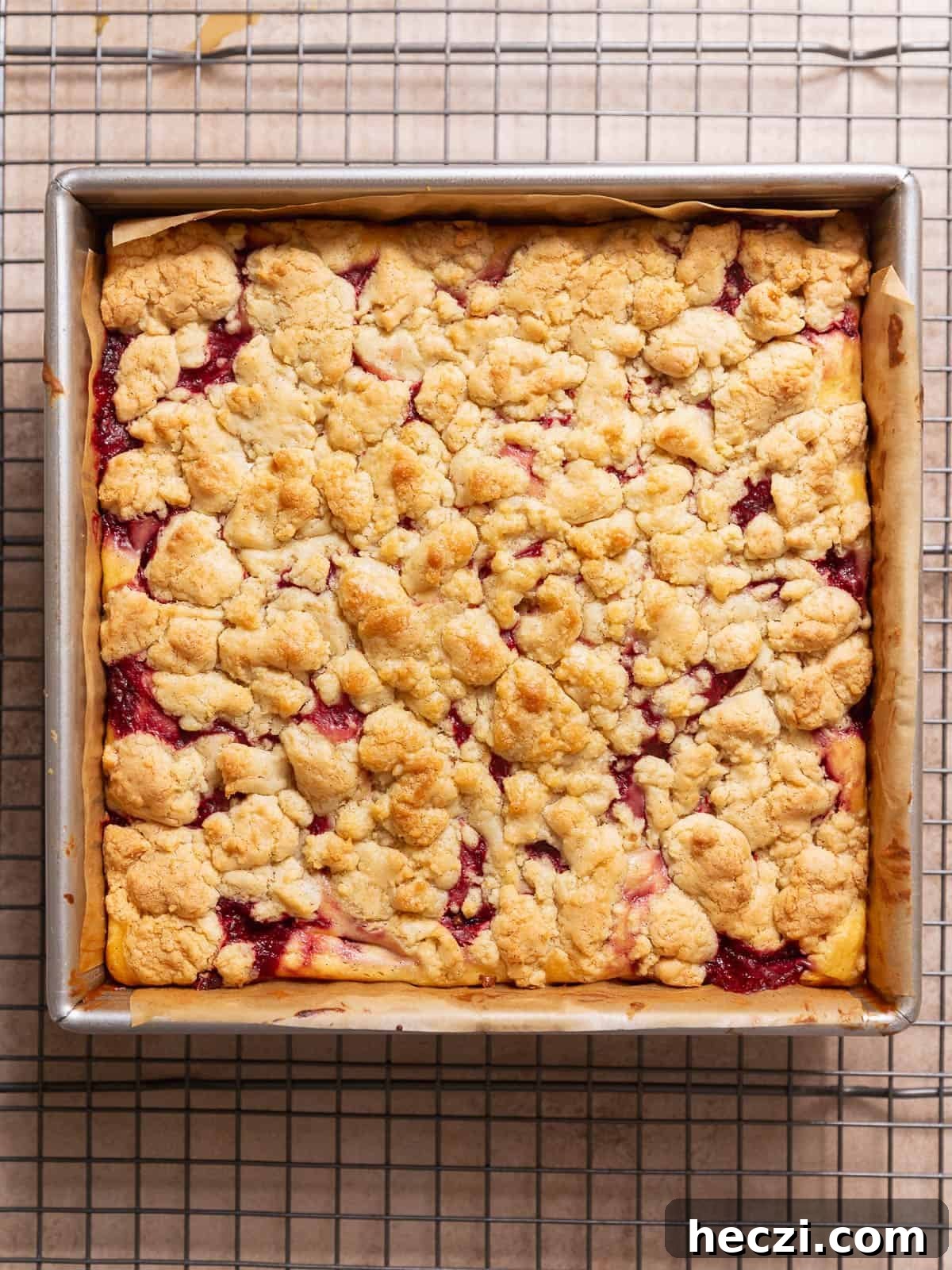 Baked strawberry cheesecake bars cooling in a square metal pan.