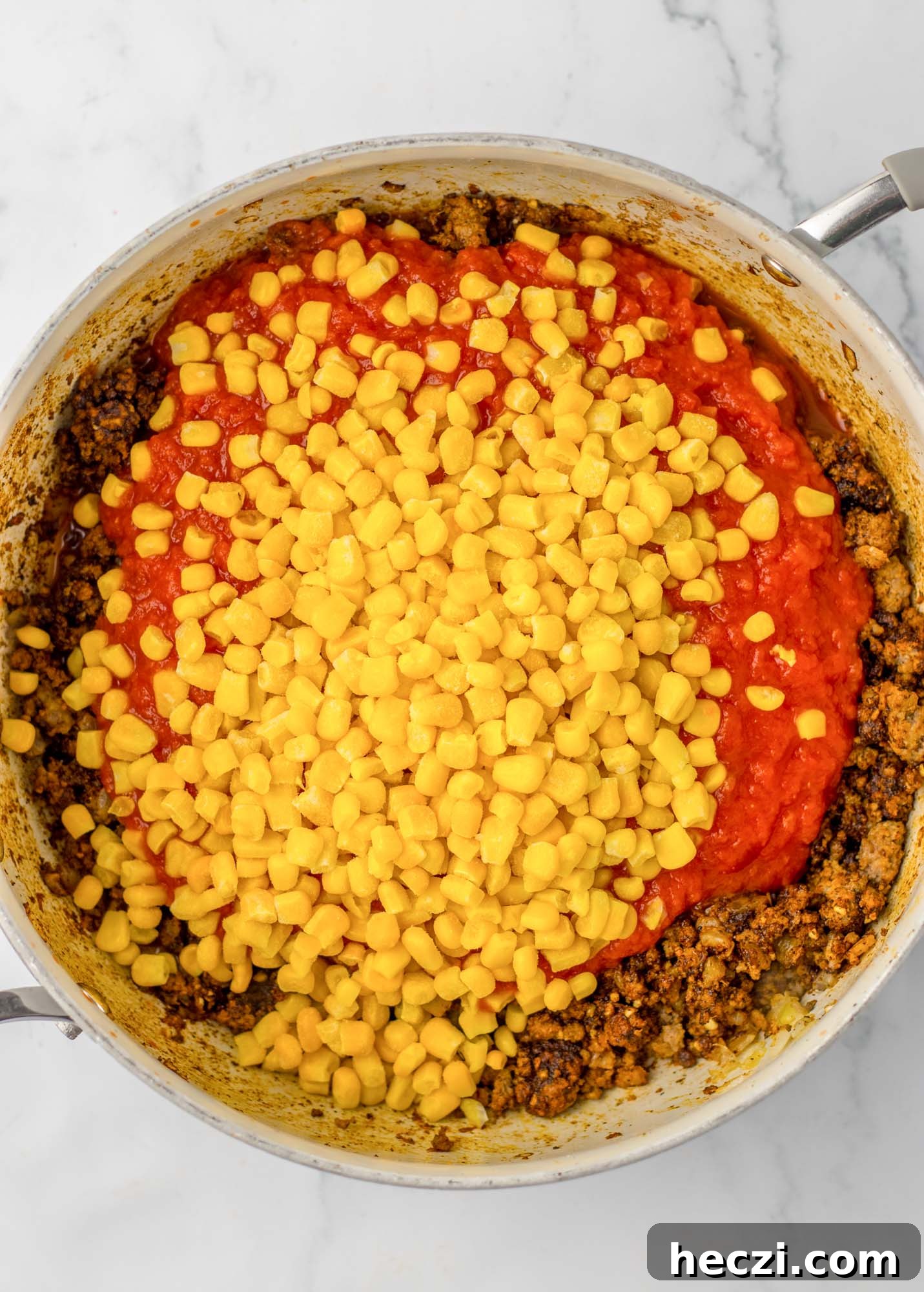 Added tomato sauce and corn to a skillet of browned beef