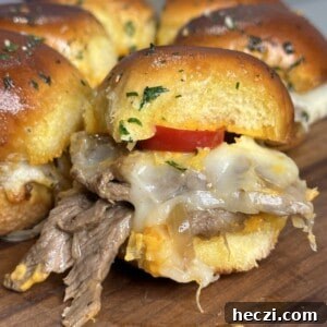 Close-up of a slider sandwich with melted cheese and sliced beef on a wooden board