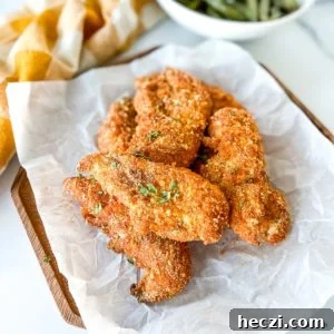 Crispy Shake-and-Bake Chicken Recipe for Oven or Air Fryer 8 shake and bake chicken tenders placed on a parchment paper on top of a wood serving plate.