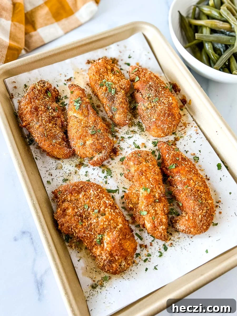 Crispy Shake-and-Bake Chicken Recipe for Oven or Air Fryer 3 Crispy baked panko chicken tenders on parchment lined baking pan.