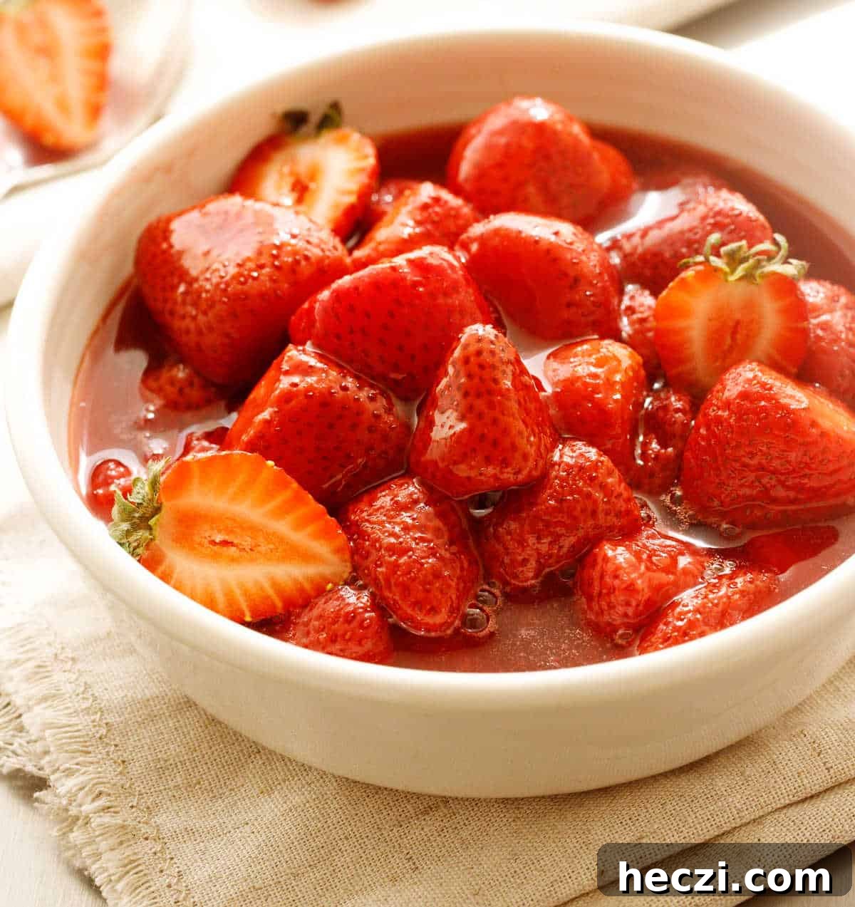 4-Ingredient Strawberry Compote Recipe for Fresh Homemade Jam 2 Beige surface with white bowl containing strawberry compote.