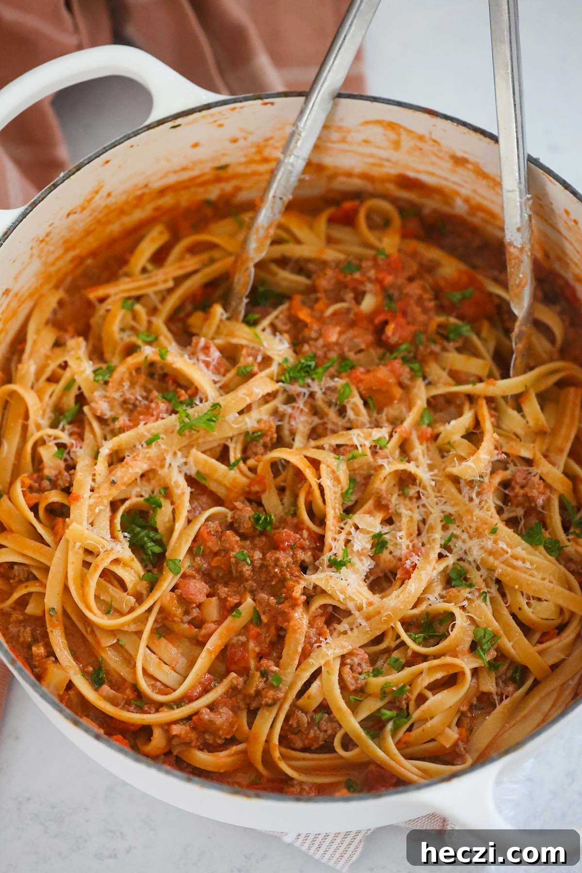 Pasta in a large pot with tongs.