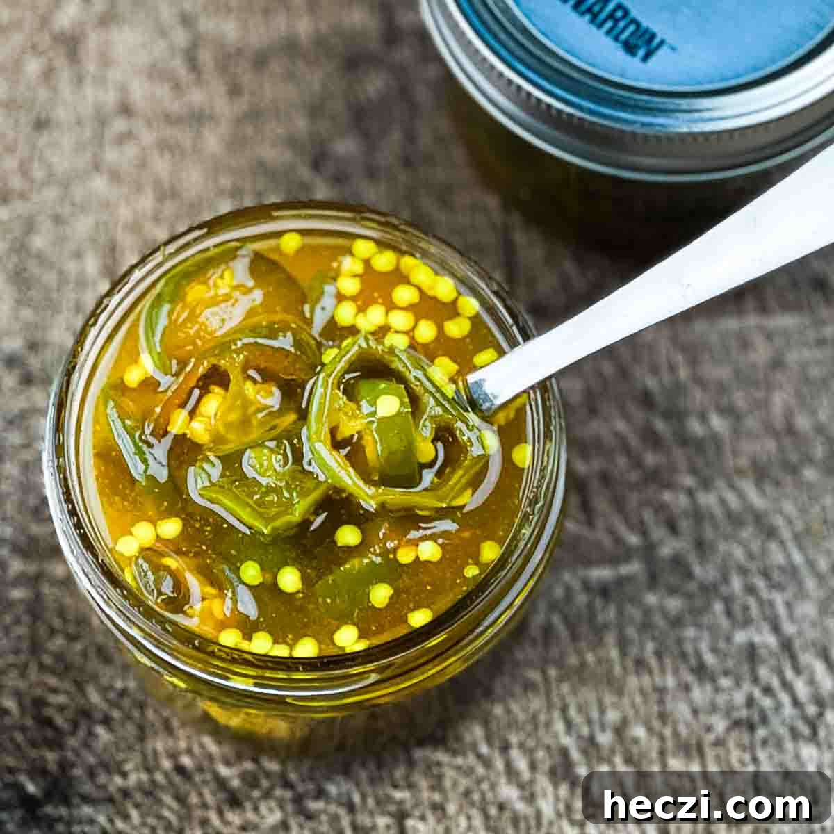 Small-Batch Cowboy Candy Canning Recipe for Spicy Candied Jalapeños 2 An open jar of cowboy candy with a spoon in it.