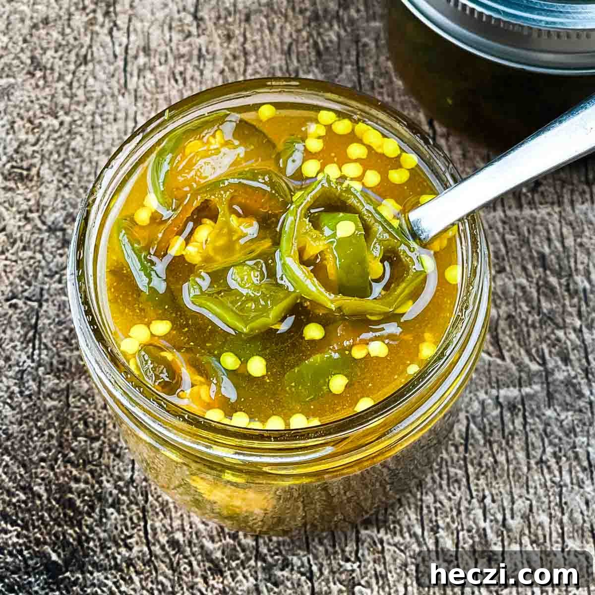 Small-Batch Cowboy Candy Canning Recipe for Spicy Candied Jalapeños 11 A spoon lifting up some candied jalapeno slices.