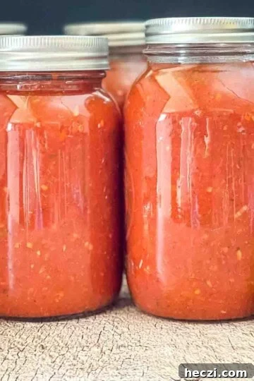 Jars of homemade canned spaghetti sauce on a wooden table.