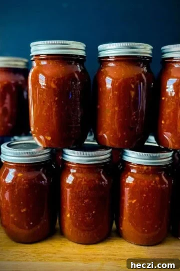 Homemade canned salsa stacked on a wooden counter.