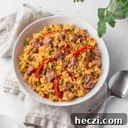 Overhead shot of vegan Arroz Valenciana in a white bowl with a spoon and natural linen.