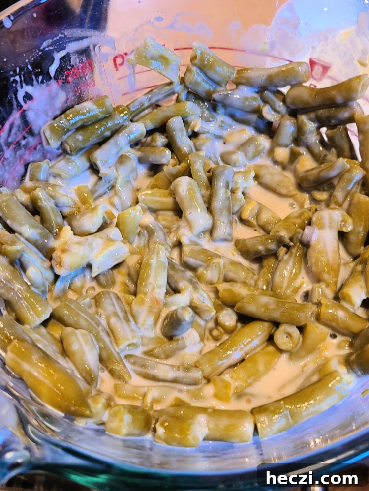 Green beans mixed with cream of mushroom soup in pyrex measuing glass 