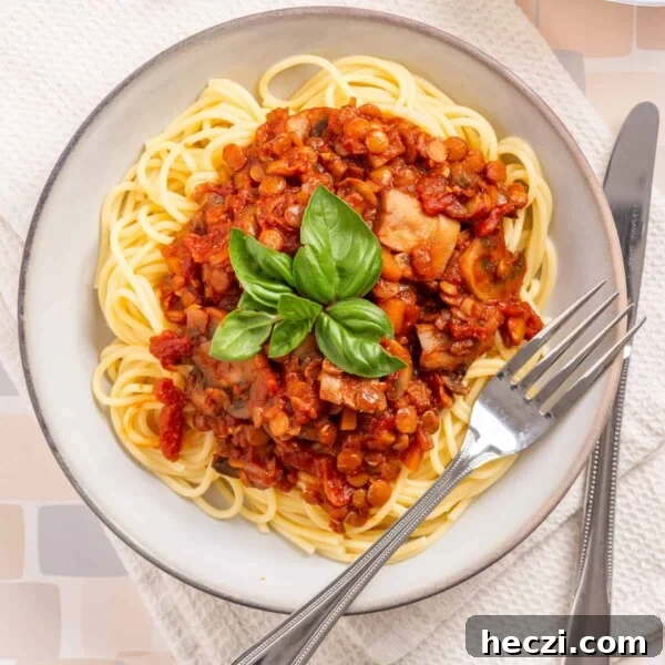 An overhead image of vegan bolognese with spaghetti in a serving bowl with a fork on the side.