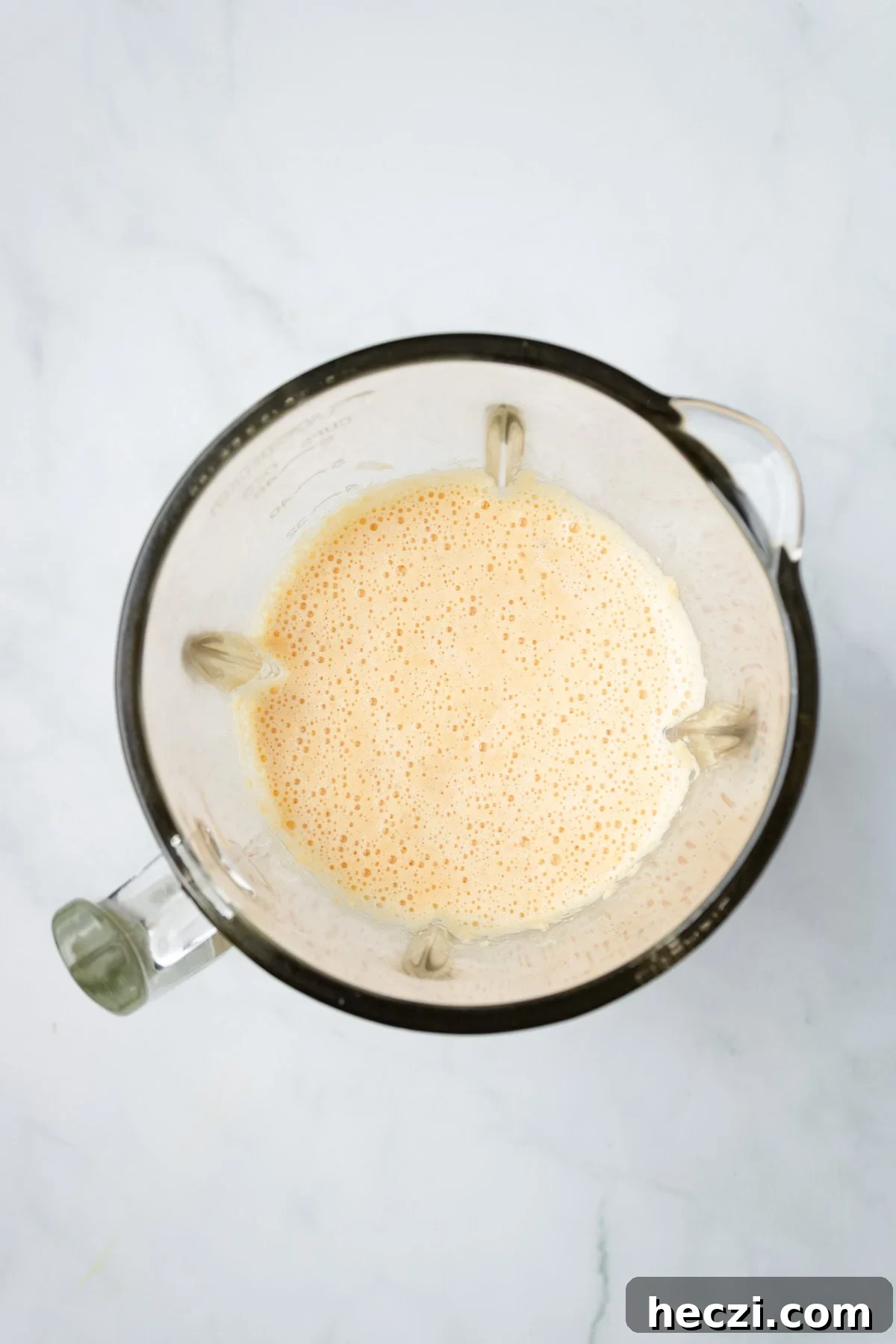 An overhead image of blending lentils with water, turmeric, salt, and cumin seeds until smooth and pourable.