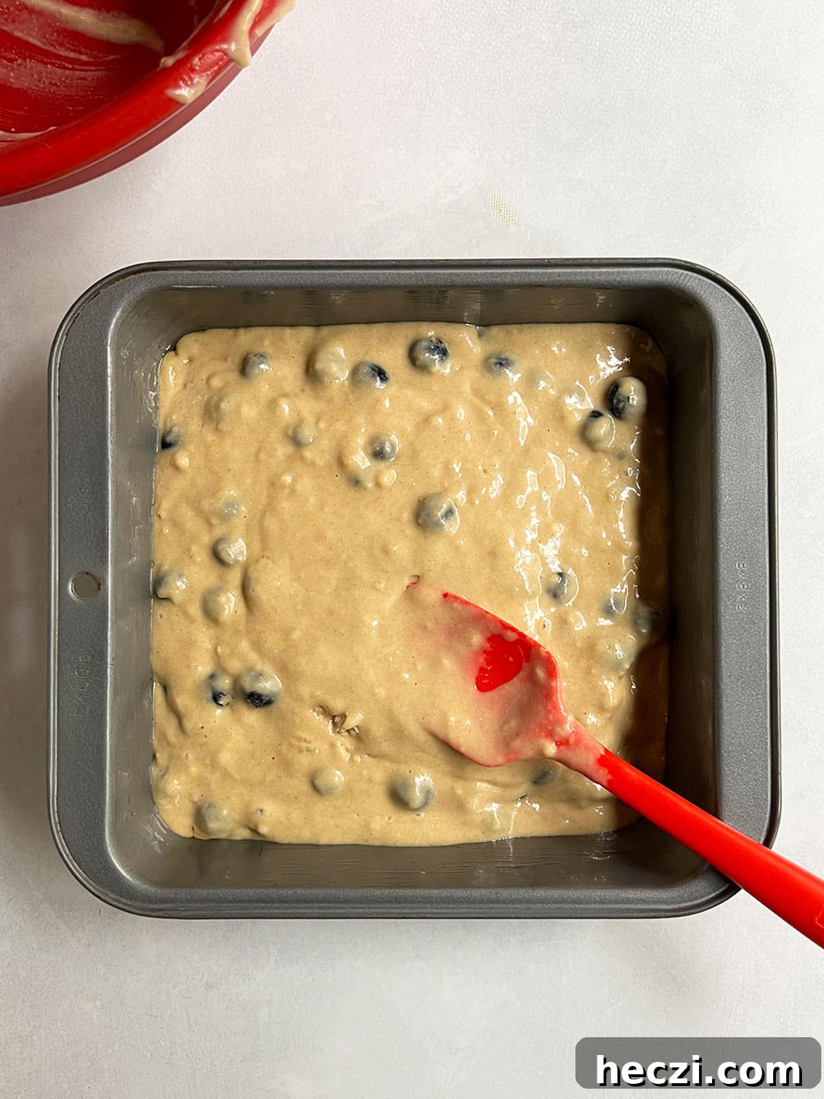 Blueberry loaf cake batter in the square cake pan ready to bake.