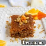 Honey orange cake on a white plate with slices of citrus in the background.