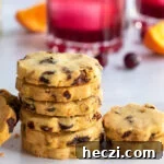 Close up of a stack of cookies on a white plate with a cocktail in the background.