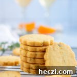 Stack of orange shortbread cookies of different sizes with cocktails in the background.