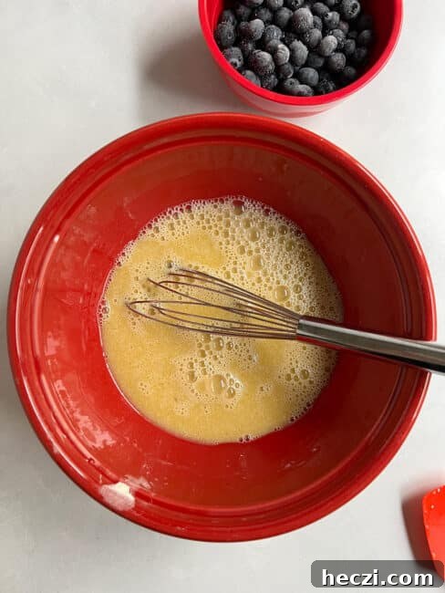 Wet ingredients mixed in the red bowl with the whisk in the bowl.
