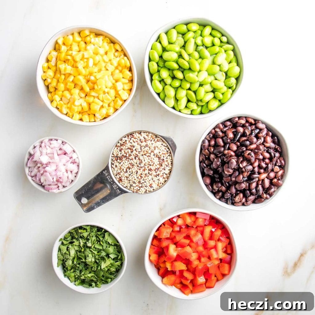 small bowls with ingredients for quinoa salad: yellow corn, green edamame, black beans, minced shallot, chopped fresh cilantro, raw uncooked quinoa, black beans, diced red peppers