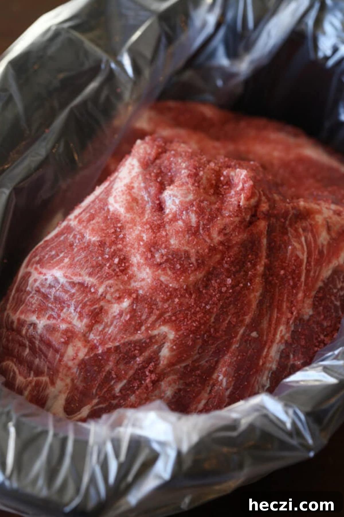 A boneless pork butt roast in a lined crock pot.