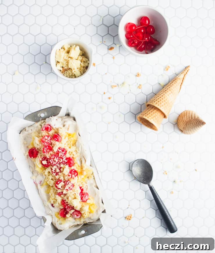 Pineapple Upside-Down Cake Ice Cream (No-Churn Recipe) 4 ice cream in a pan with cherries, pineapple and cones nearby