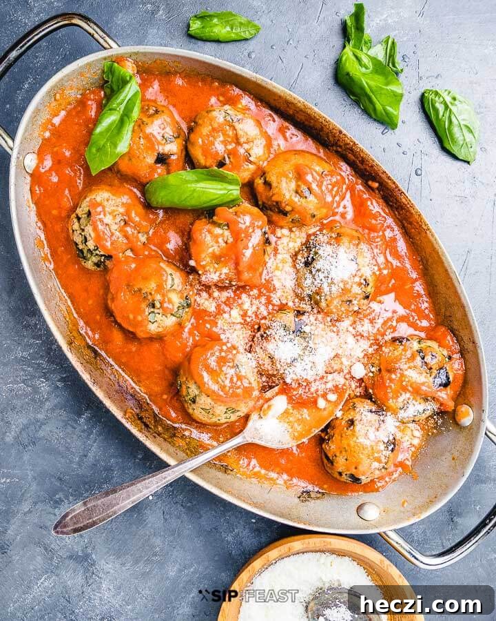 Eggplant Meatballs - sipandfeast.com #eggplantmeatballs #italianrecipes #eggplantrecipes Eggplant meatballs in oval pan with sprinkled basil leaves and bowl of Pecorino Romano cheese.