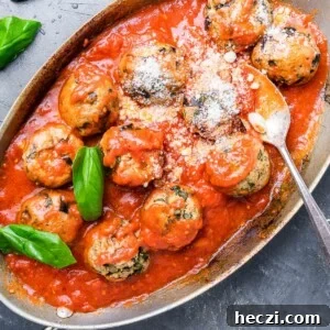 Eggplant Meatballs with Basil and Pecorino Romano Cheese 2 Eggplant meatballs in oval pan sprinkled with Pecorino Romano and basil leaves.