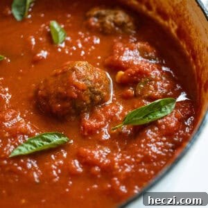 Homemade Italian Sunday Sauce Recipe for Classic Pasta Night 14 Sunday sauce with meatballs and sausage in a pot.