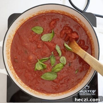 Homemade Italian Sunday Sauce Recipe for Classic Pasta Night 9 Tomatoes and basil added to the pot.