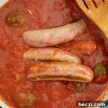 Homemade Italian Sunday Sauce Recipe for Classic Pasta Night 10 Sauce simmering with sausage and meatballs.