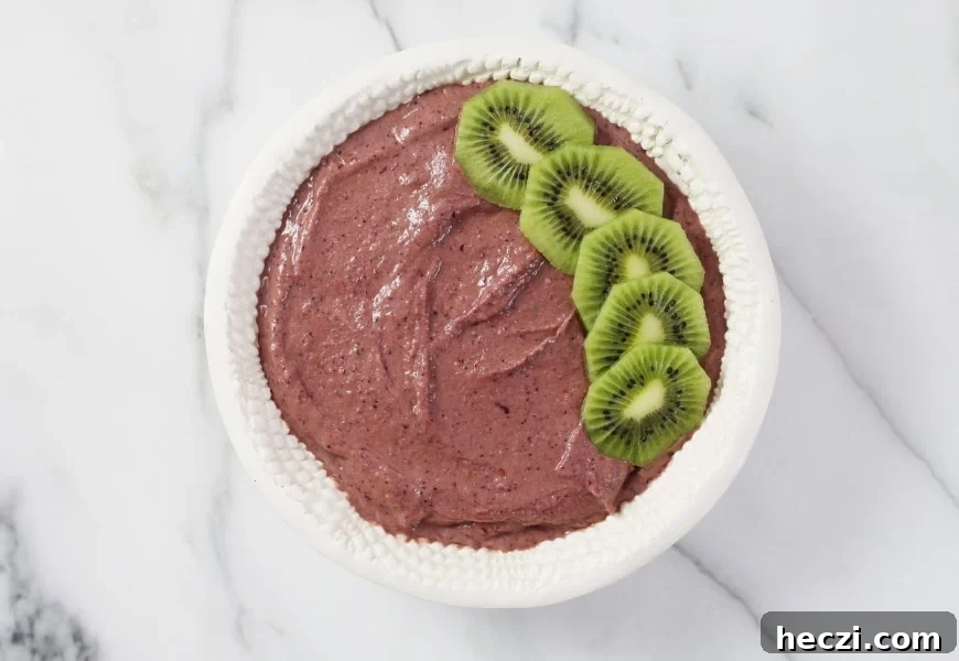 Process shot of adding fresh fruit to the top of the superfood berry smoothie bowl