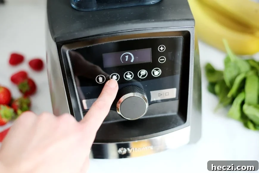 Finger pressing the "on" button on the Vitamix blender 