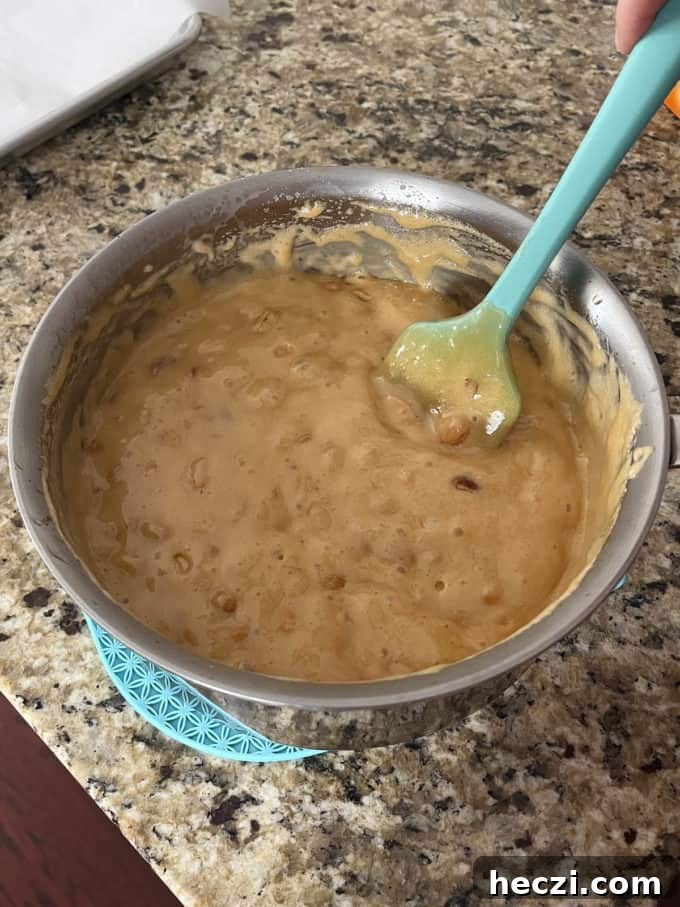 Classic Peanut Brittle Recipe: Crispy, Homemade Candy in 30 Minutes 14 peanut brittle mixture in a pot on a counter top with a rubber spatula in it