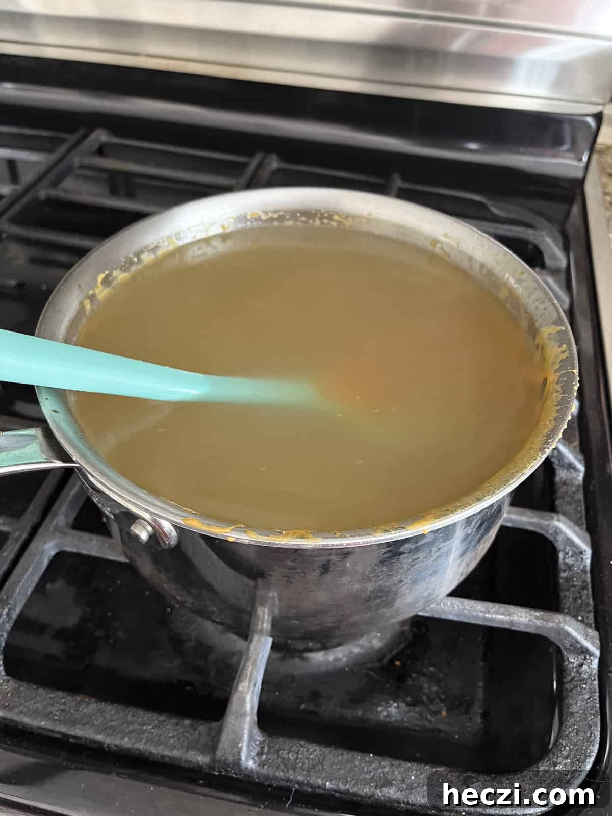 Classic Peanut Brittle Recipe: Crispy, Homemade Candy in 30 Minutes 16 a put on the stove full of water and leftover candy from making peanut brittle with a rubber spatula in it