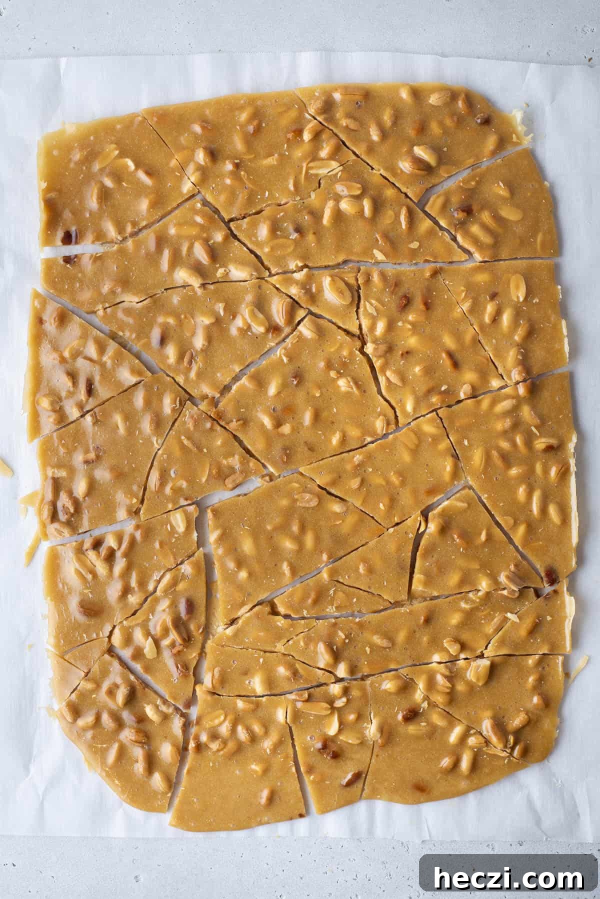 Classic Peanut Brittle Recipe: Crispy, Homemade Candy in 30 Minutes 6 peanut brittle broken into pieces on a baking sheet lined with parchment paper