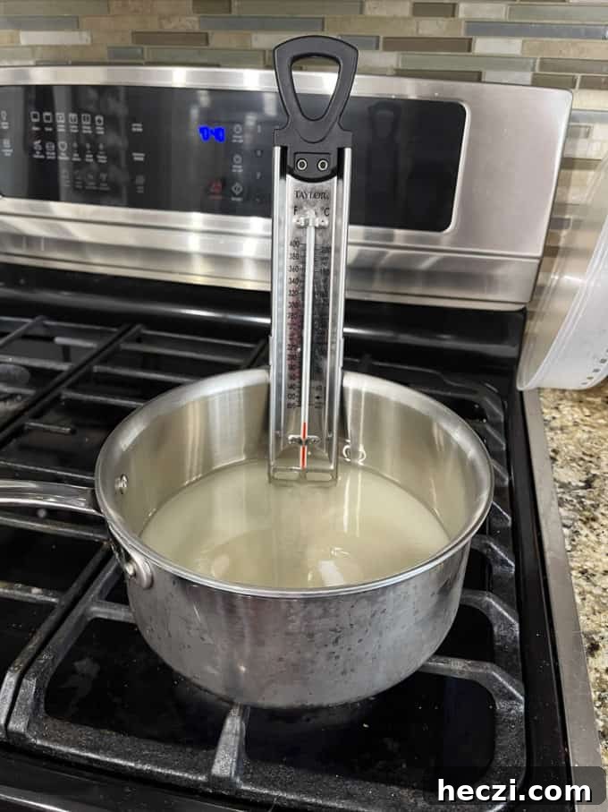 Classic Peanut Brittle Recipe: Crispy, Homemade Candy in 30 Minutes 8 a pot on a stovetop with granulated sugar, water and corn syrup mixed in it and candy thermometer attached to the side