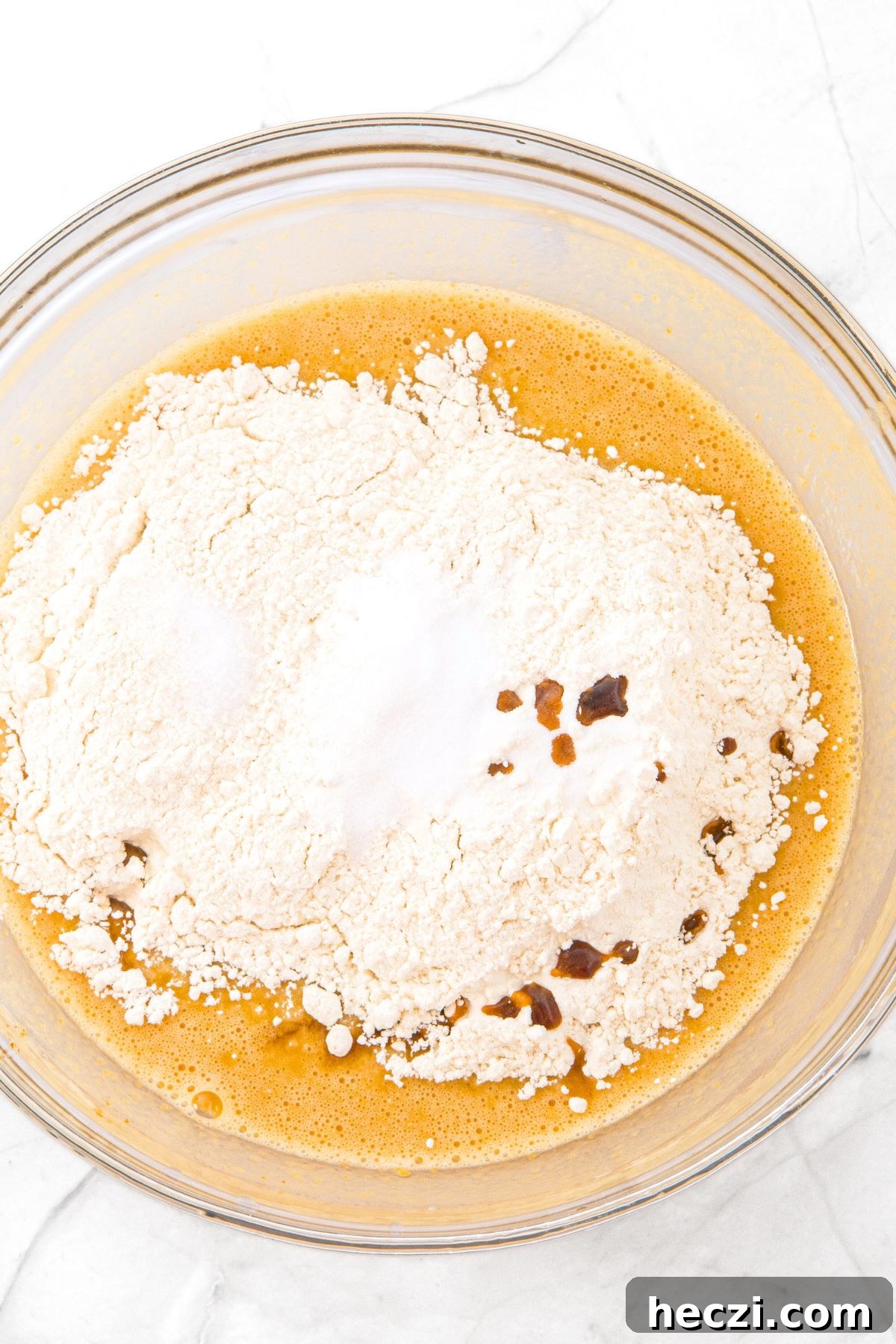 Flour on top of a pale yellow liquid mixture.