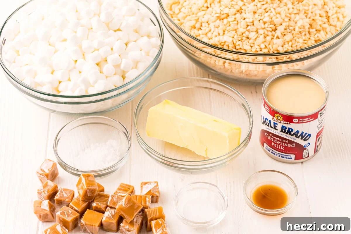 Ingredients to make salted caramel rice krispie treats on a white wood table.