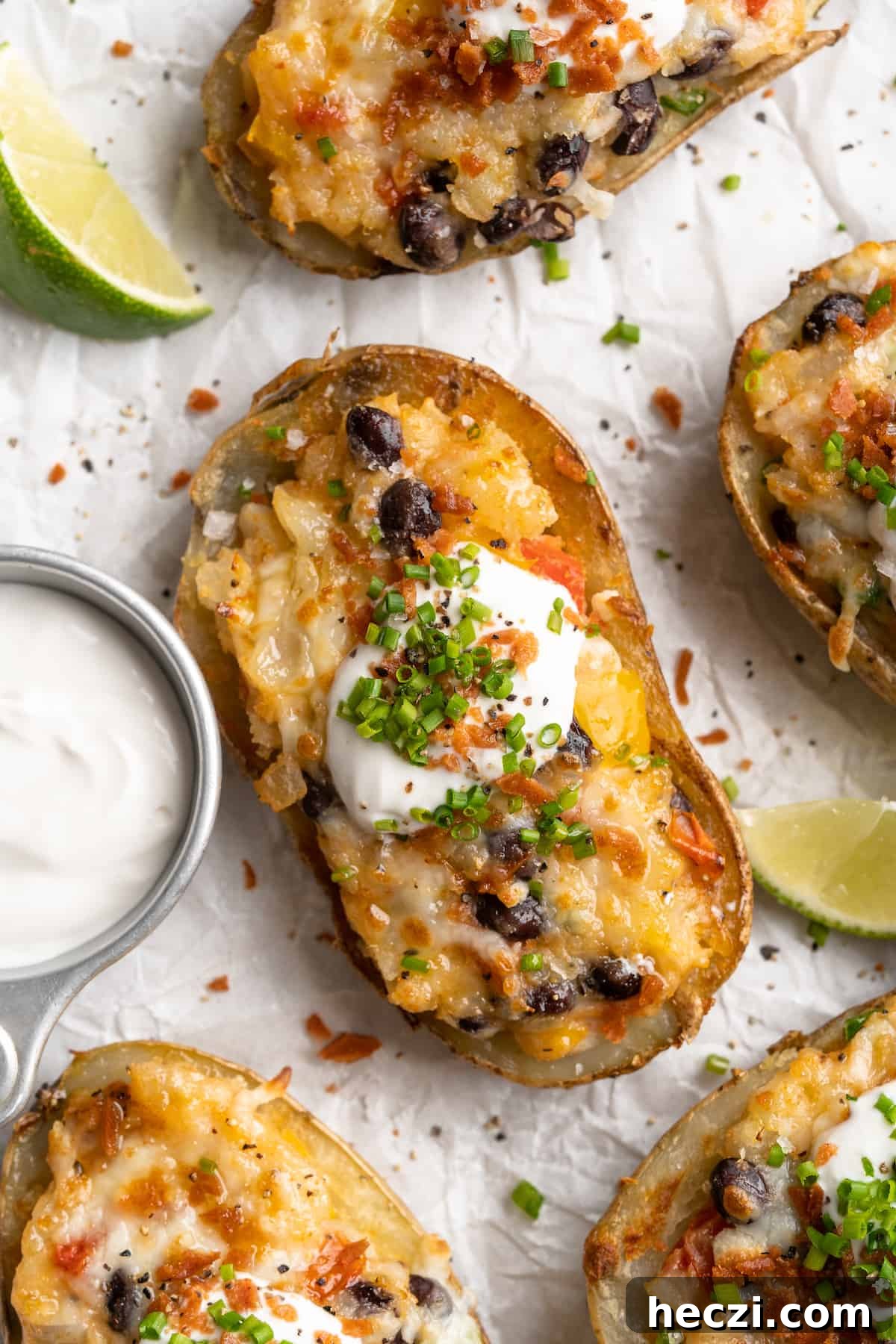 These crispy loaded potato skins are filled with veggies, black beans, vegan cheese, and sour cream. A vegan appetizer that doubles as a meal! Overhead view of loaded potato skin topped with chives, vegan bacon, and sour cream