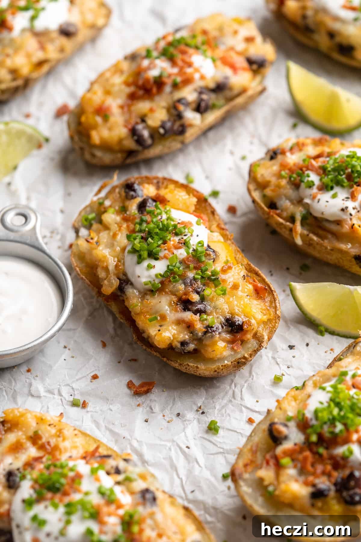 Serve with vegan sour cream and lime. Loaded potato skins on parchment paper with cup of vegan sour cream and lime wedges